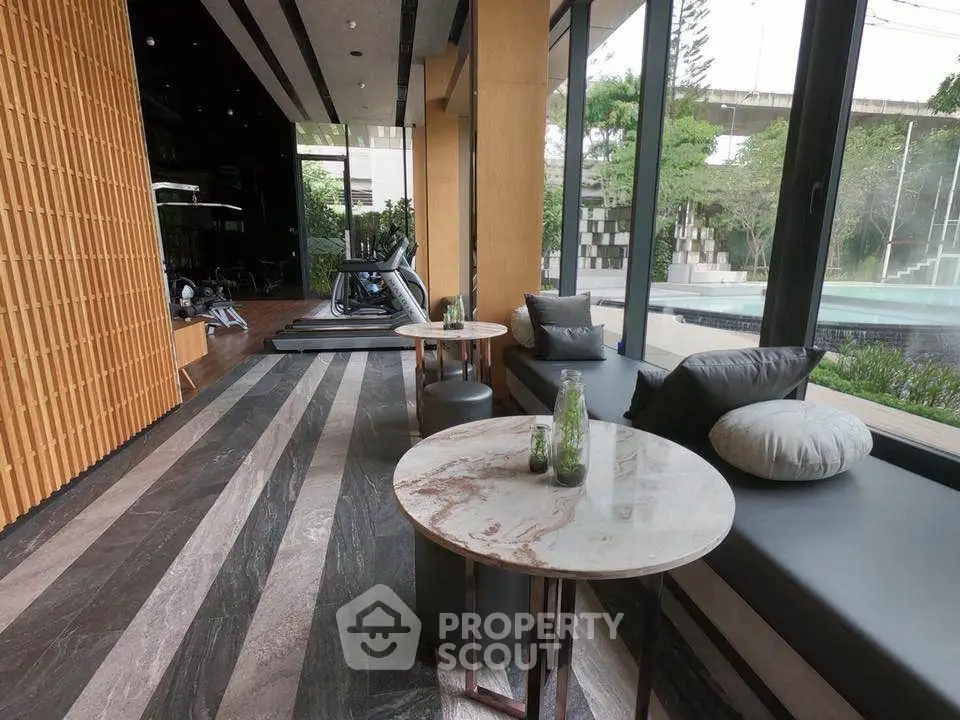 Luxurious gym with modern equipment and pool view in upscale residential building.