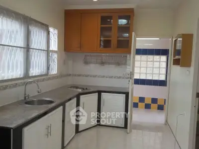Spacious kitchen with modern cabinetry and dual sink, featuring open layout and ample natural light.