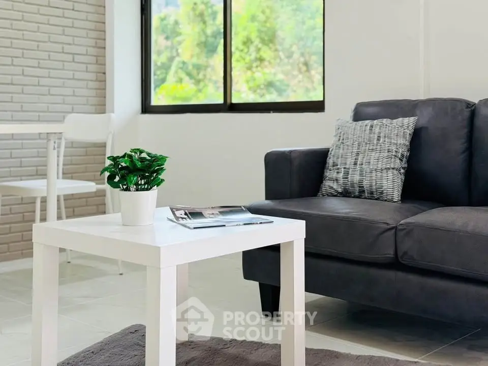 Modern living room with sleek black sofa and white coffee table, bright natural light.