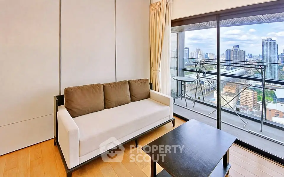 Modern living room with city view and spacious balcony in high-rise apartment.