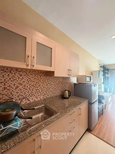 Modern kitchen with sleek cabinetry and mosaic backsplash in cozy apartment