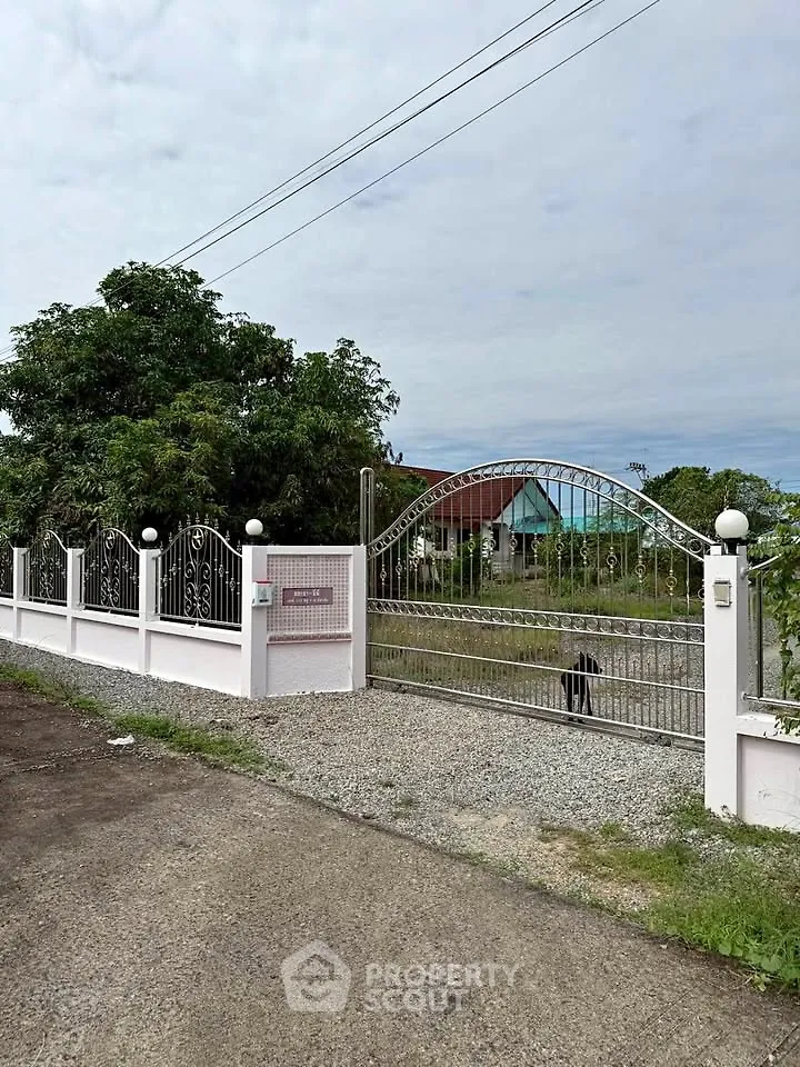 Charming gated entrance with lush greenery and spacious driveway, perfect for privacy and security.