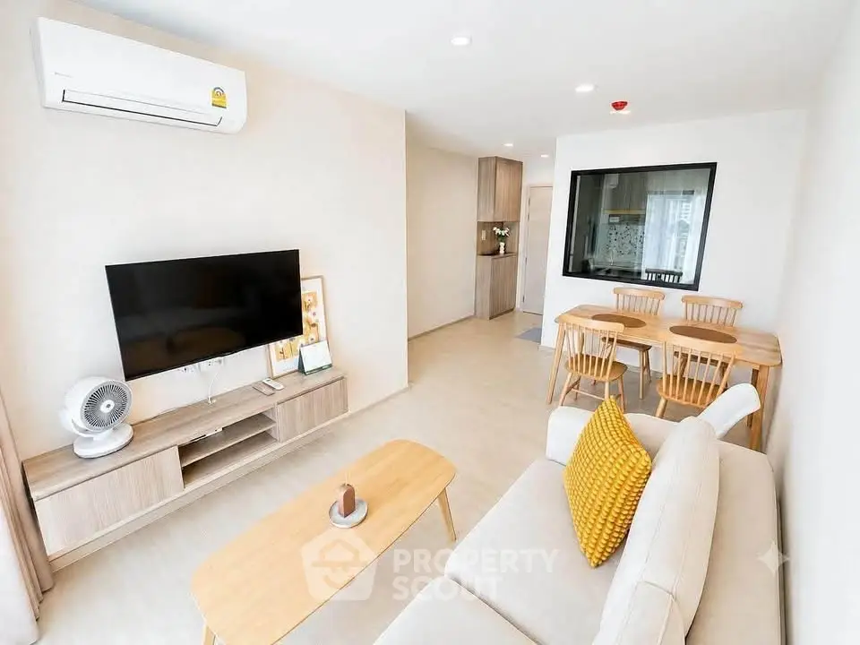 Modern living room with stylish furniture and open layout, featuring a cozy dining area and sleek TV setup.