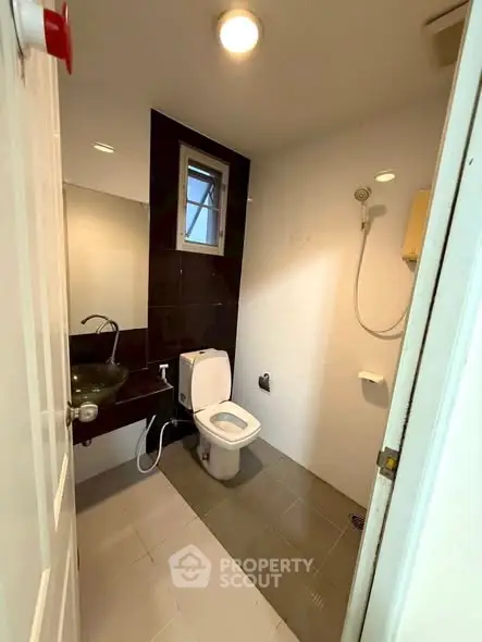 Modern bathroom with sleek fixtures and contemporary design, featuring a glass sink and shower area.