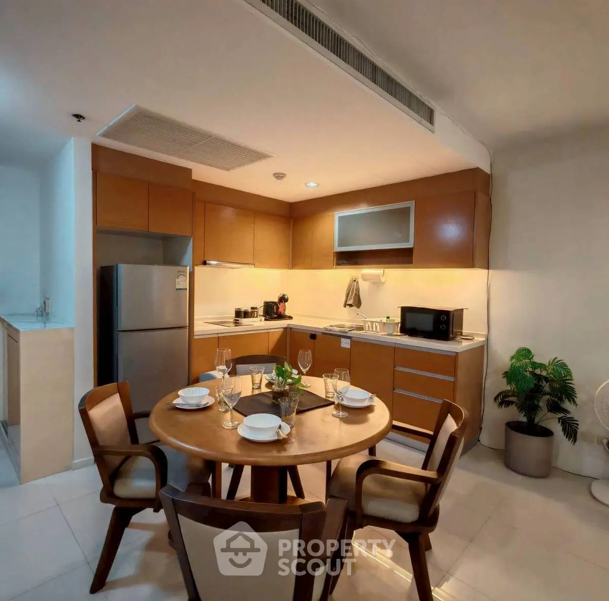 Modern kitchen with wooden cabinets and dining area, featuring sleek appliances and elegant decor.