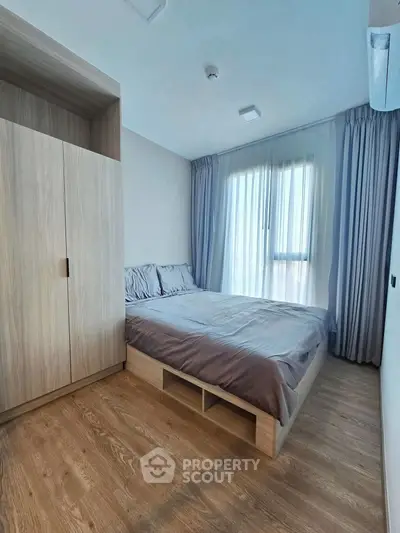 Modern bedroom with wooden flooring and large window for natural light
