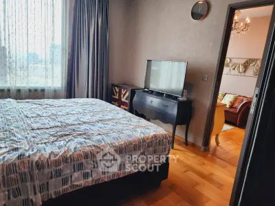Charming bedroom with stylish decor and a glimpse into a cozy living room, perfect for modern living.