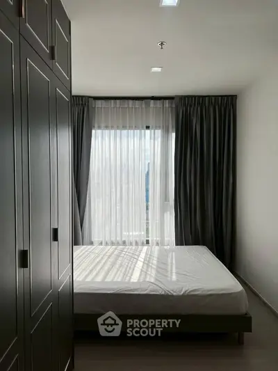Modern bedroom with large window and sleek wardrobe in a stylish apartment.