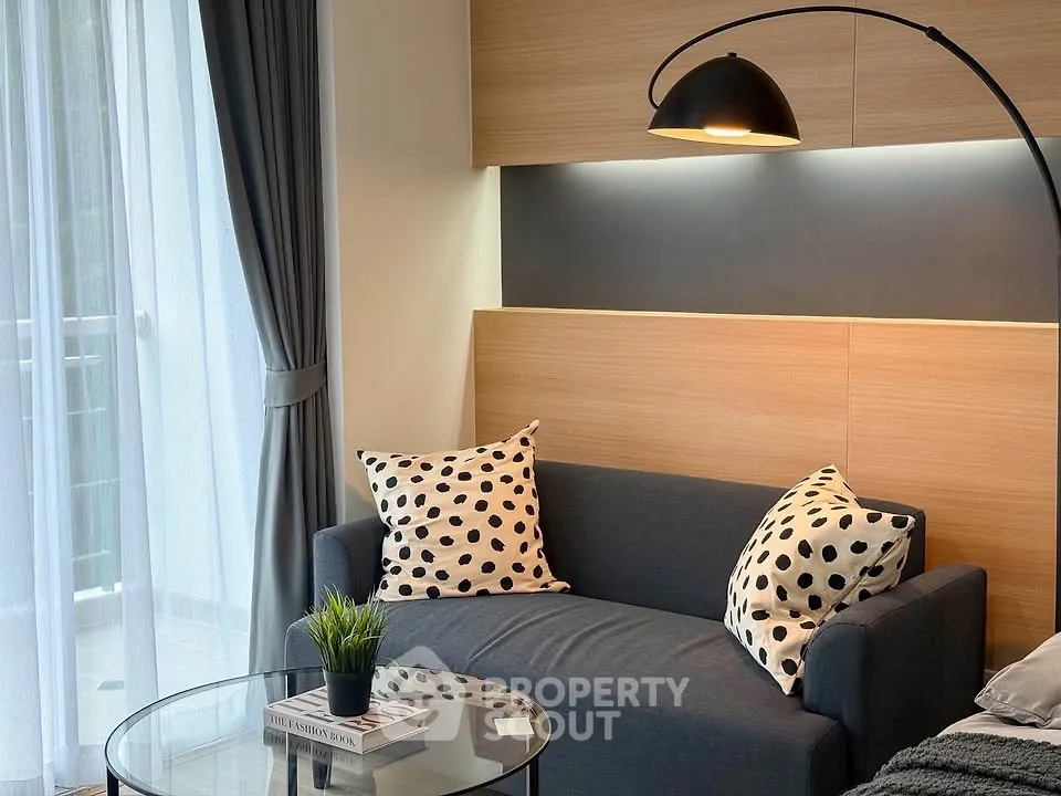 Modern living room with stylish sofa and floor lamp, featuring a cozy balcony view.