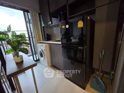Modern kitchen with sleek appliances and balcony view, featuring a fridge, washing machine, and stylish cabinetry.