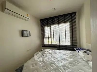 Cozy bedroom with large window and air conditioning in modern apartment.