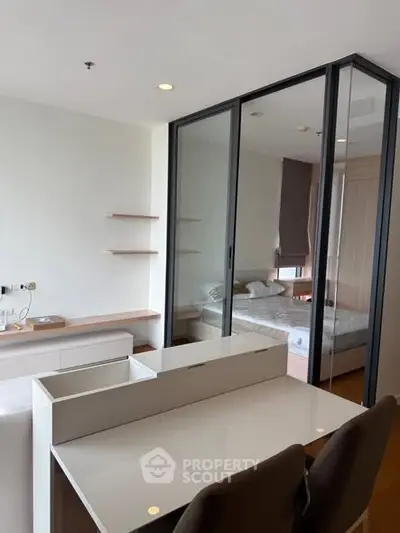 Modern studio apartment with glass partition separating bedroom and living area.