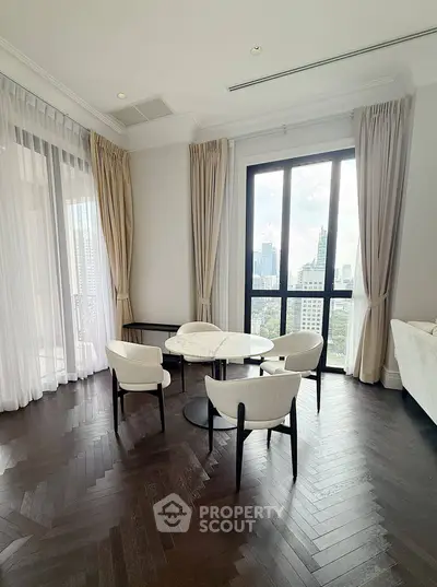 Elegant living room with city view, featuring dark wood floors and modern furniture.