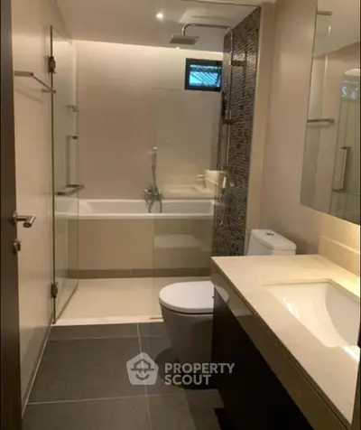 Modern bathroom with glass shower and bathtub in elegant design.