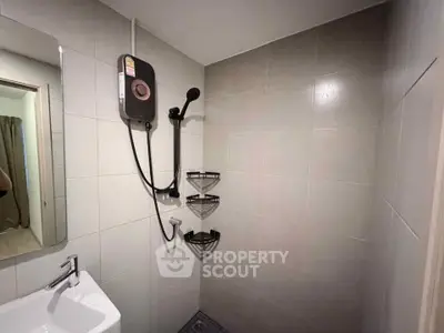 Modern bathroom with sleek shower and compact sink in minimalist design.