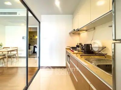 Modern kitchen with sleek cabinetry and open layout leading to dining area.