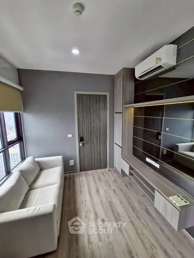 Modern living room with sleek design, featuring a comfortable sofa and built-in storage under air conditioning.