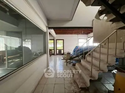 Spacious interior with unique staircase and large windows for natural light.