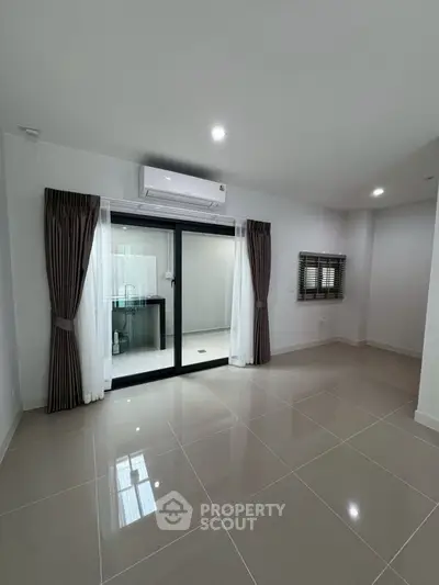 Spacious modern living room with sleek tile flooring and large windows for natural light.