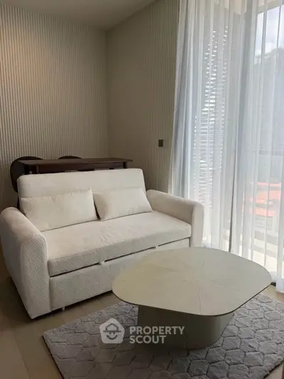 Modern living room with cozy white sofa and stylish coffee table near large window with sheer curtains.