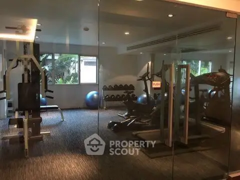 Modern gym with state-of-the-art equipment and glass walls in a luxury residential building.