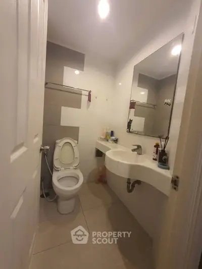 Modern bathroom with sleek fixtures and large mirror in a cozy apartment.