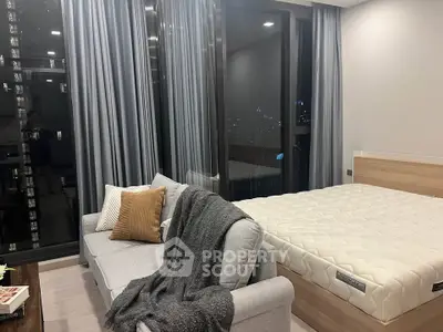 Modern bedroom with large windows and cozy seating area in a stylish apartment.
