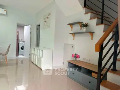 Modern living room with stylish staircase and laundry area, perfect for contemporary living.