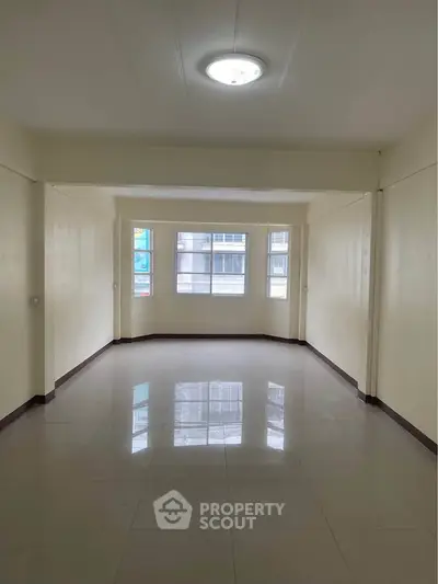 Spacious empty room with large windows and glossy tiled floor, ideal for customization.