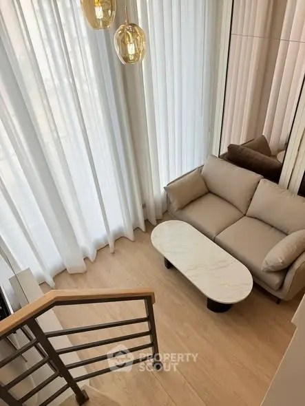 Modern living room with elegant sofa and stylish coffee table, featuring floor-to-ceiling windows and chic lighting.