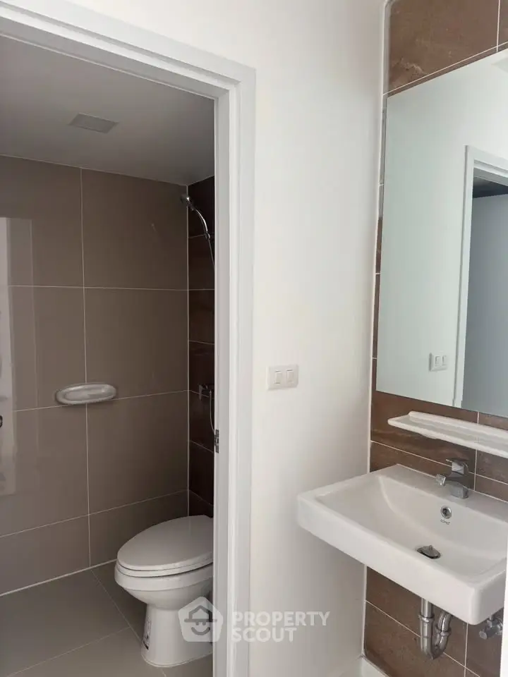Modern bathroom with sleek fixtures and neutral tiles, featuring a compact design.