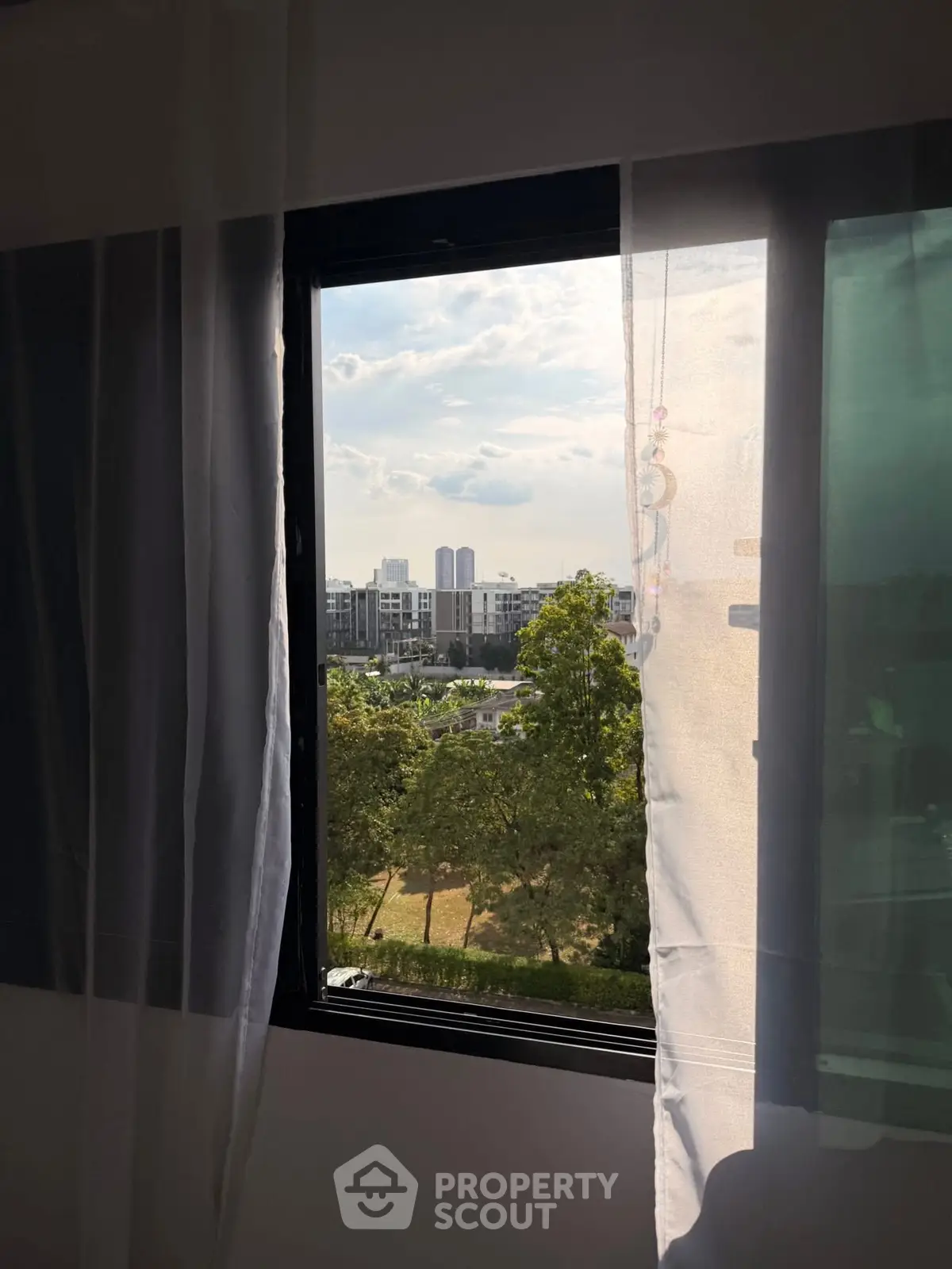 Scenic view from window overlooking cityscape and greenery, perfect for urban living.