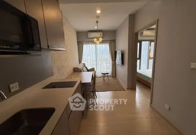 Modern open-layout apartment with kitchen and living area, featuring large windows and stylish decor.