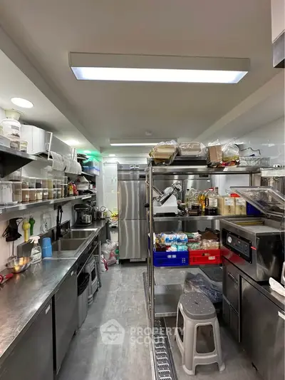 Spacious commercial kitchen with stainless steel appliances and ample storage space.