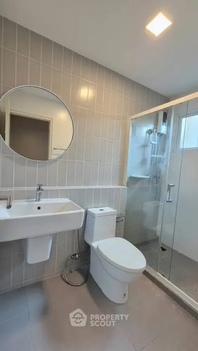 Modern bathroom with sleek fixtures and glass shower enclosure in a contemporary home.