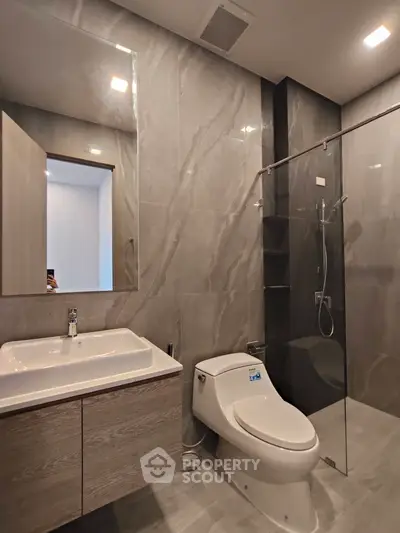 Modern bathroom with sleek design, featuring a glass shower and elegant fixtures.