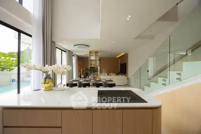Luxurious open-plan kitchen and living area with pool view, featuring modern design and elegant decor.