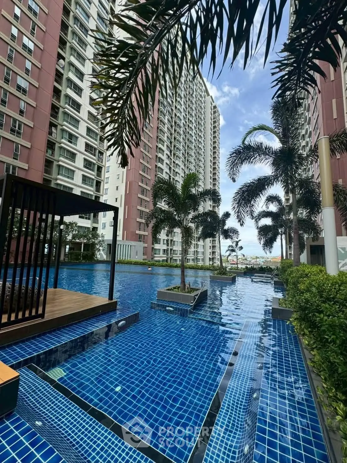 Luxurious high-rise apartment with stunning pool and lush palm trees, offering a serene urban oasis.