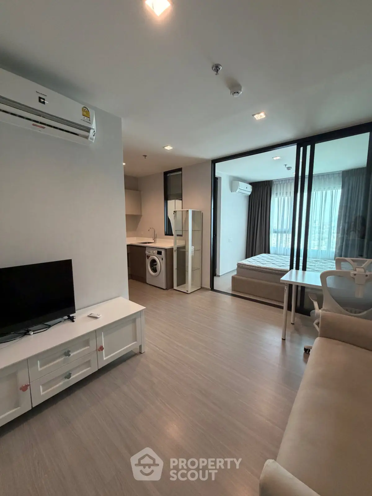 Modern apartment interior with living room, kitchen, and bedroom featuring sleek design and natural light.