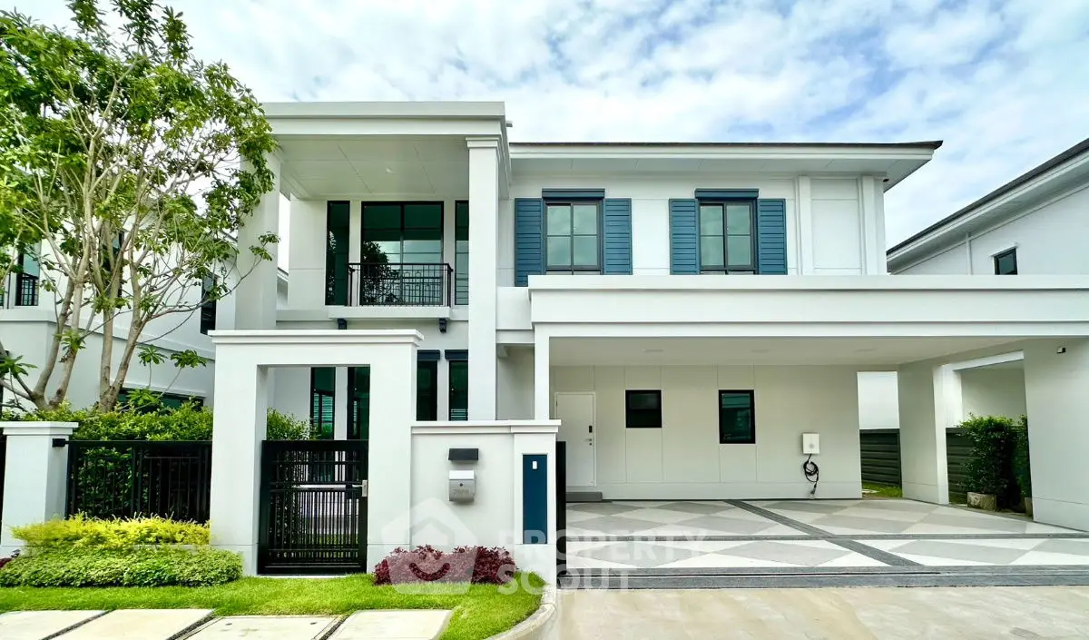 Modern two-story white house with lush landscaping and spacious driveway.