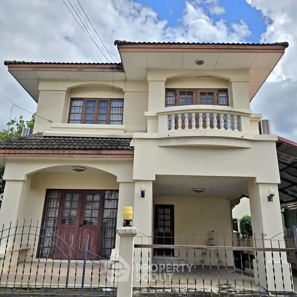 Charming two-story house with balcony and gated entrance, perfect for family living.