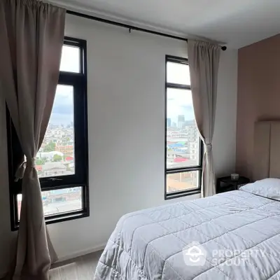 Bright bedroom with large windows offering stunning city views.