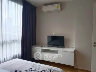 Modern bedroom with air conditioning and city view, featuring a sleek TV setup and elegant curtains.