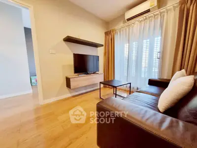 Modern living room with sleek furniture and natural light, featuring a wall-mounted TV and stylish decor.