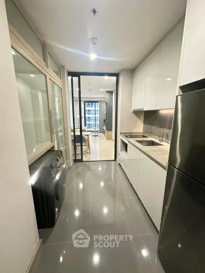 Modern kitchen with sleek appliances and open layout leading to a bright living area.
