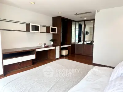 Spacious bedroom with modern built-in desk and wardrobe, featuring elegant wood finishes.