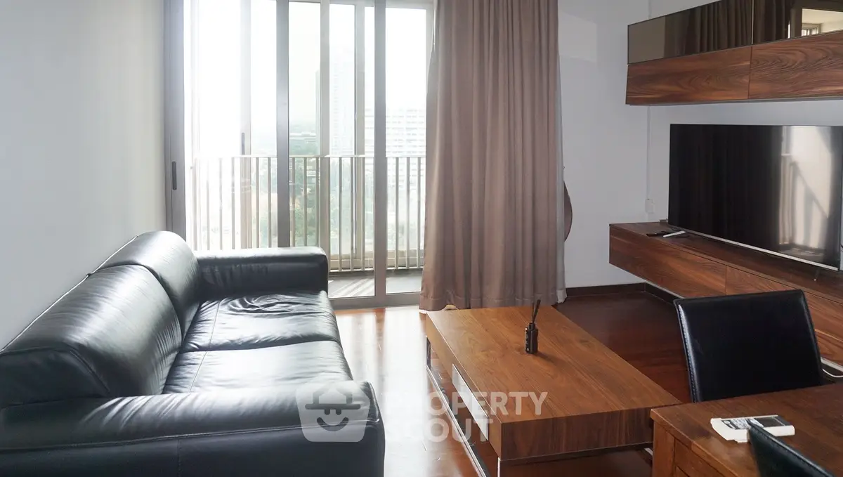 Modern living room with sleek leather sofa and wooden furniture, featuring a large window with city view.