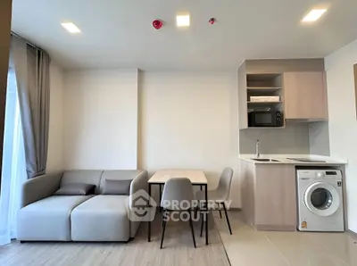 Modern living room with compact kitchen and washing machine in stylish apartment.