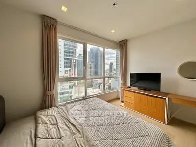 Modern bedroom with city view, featuring large windows, TV, and stylish furniture.