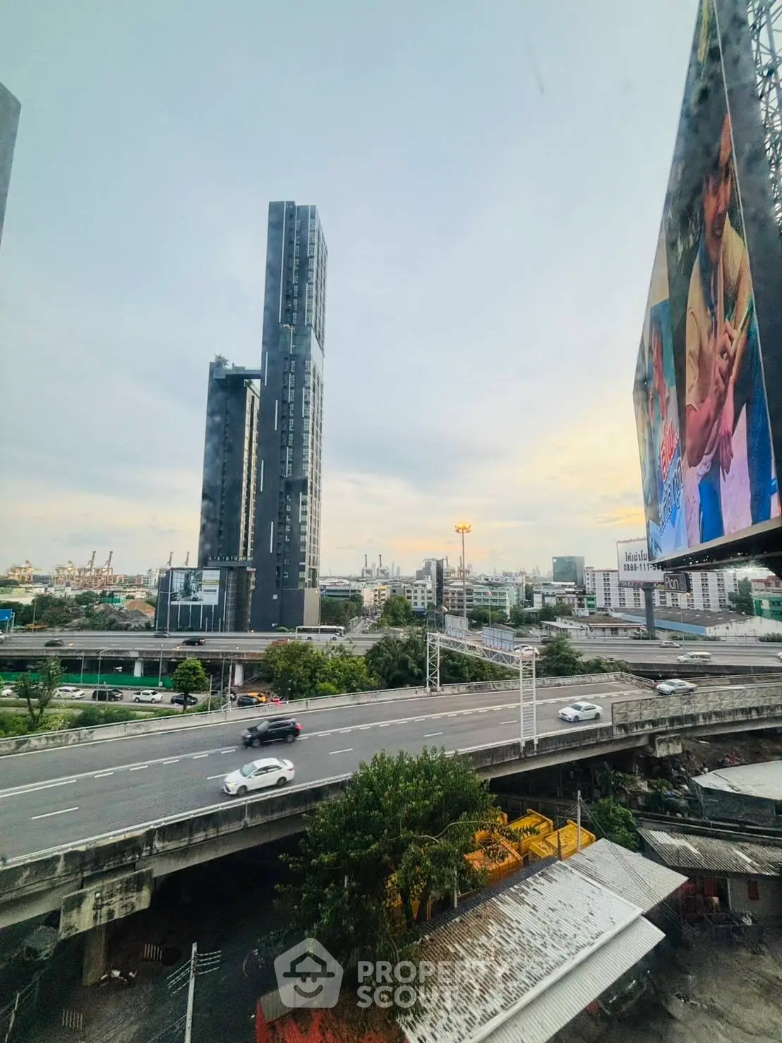 Stunning cityscape view with modern high-rise buildings and busy highway at sunset.